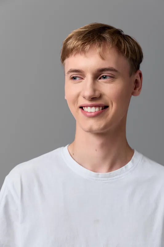 Smiling man in a white shirt against a neutral backdrop conveys friendly confidence, approachable style and everyday professionalism for lifestyle and corporate use in studio lighting.