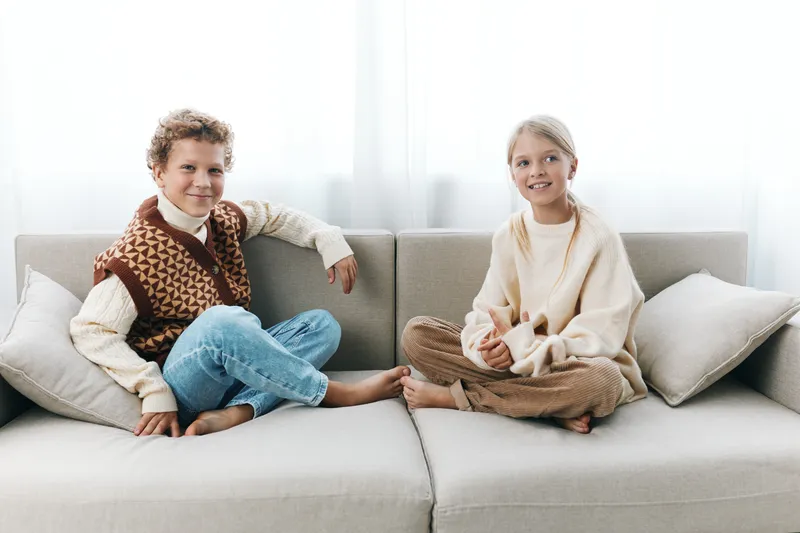 Authentic scene of children at home, a playful moment on a soft sofa, portraying everyday school life and balanced lifestyle in a cozy bright space, capturing warmth and connection.