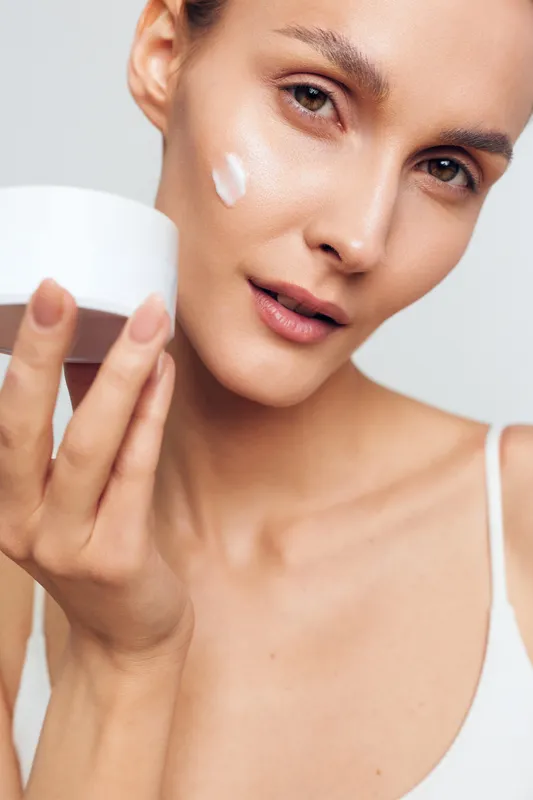 Woman skincare face cream beauty serum spa hygiene portrait routine, closeup of female applying moisturizer cream with fingers, smooth skin, clean background, calm expression