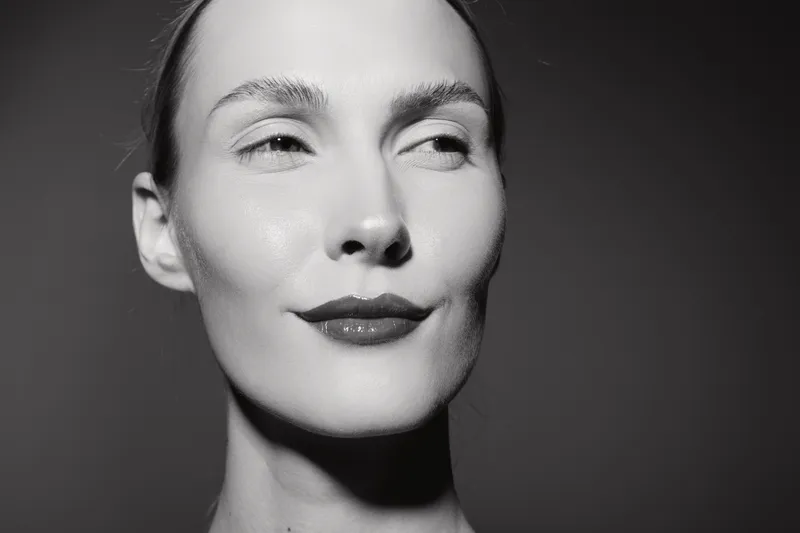 Close-up portrait of a fair skinned Caucasian woman with slicked back hair and subtle smile in black and white. Concept for beauty, confidence, and minimalism.