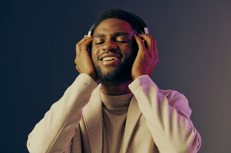 Young man enjoying music with headphones, displaying joy and relaxation against a vibrant background, representing a modern lifestyle and the power of music