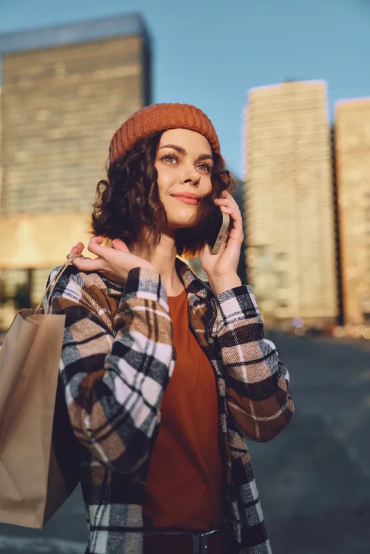 Woman shopping on city street, phone to ear portrait captures candid authenticity with golden hour glow, mindful living and emotional storytelling framing a modern urban lifestyle moment.