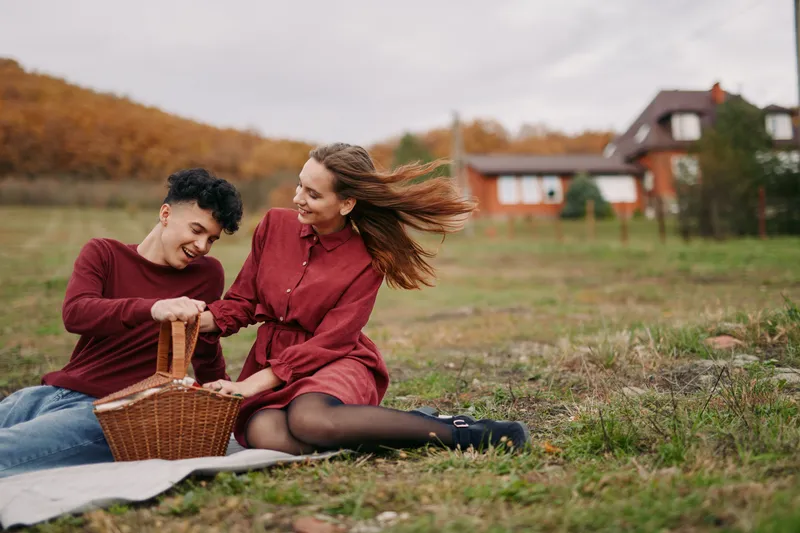 A candid couple sharing a picnic on a breezy field captures authenticity and genuine smiles, avoiding staged poses while conveying warmth, trust, and honest connection.