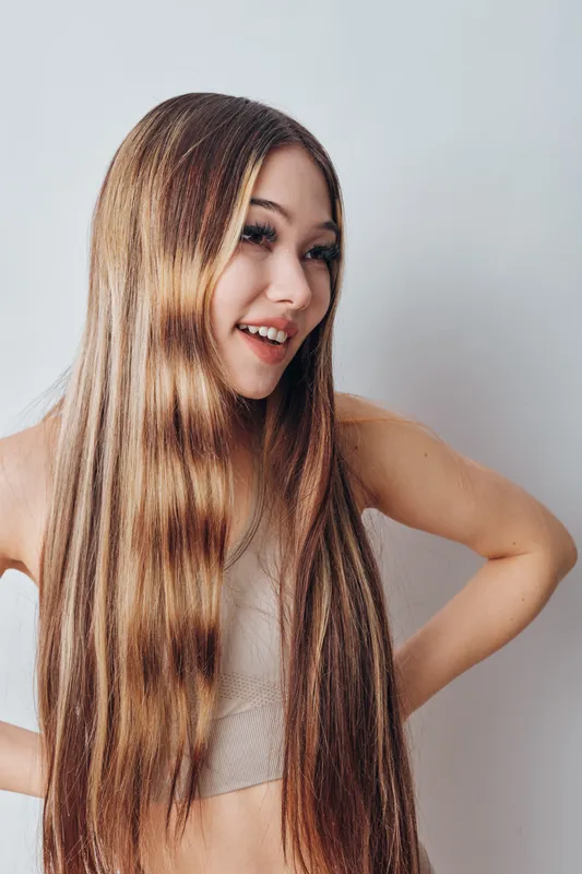 Teenage girl with long straight hair smiling and posing in casual outfit against white background. Youth, beauty, happiness and confidence with natural look and healthy hair.