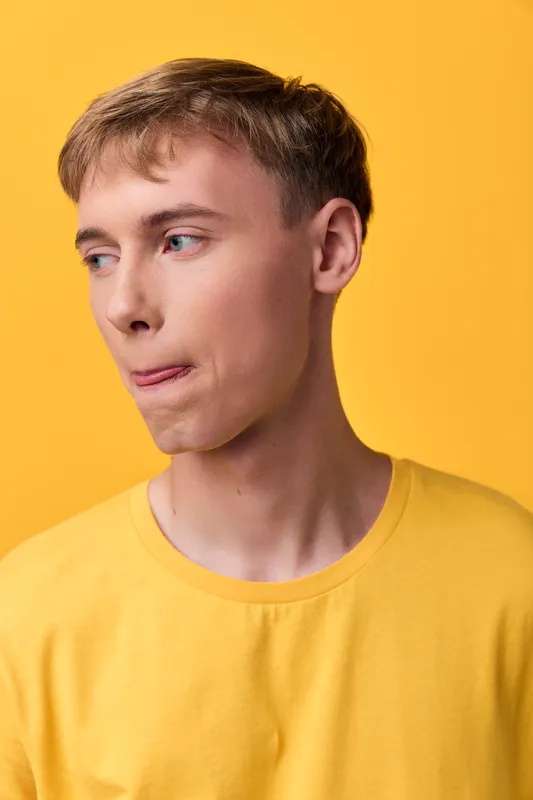 Young man, yellow shirt, casual lifestyle, studio background, fashion expression, thoughtful gaze, bright warm tones, clean composition, minimal props, suitable for lifestyle, fashion, editorial use