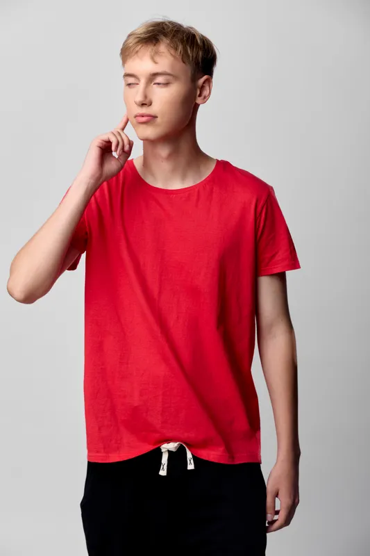 Thinking, casualwear and red shirt for fashion and everyday style. Youth model in a relaxed pose with a plain backdrop, capturing a contemporary minimal mood