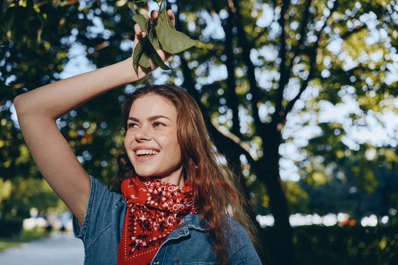 lifestyle woman in modern boho-western denim street style with film color, smiling with natural light and vibrant outdoor background, expressing joy and freedom