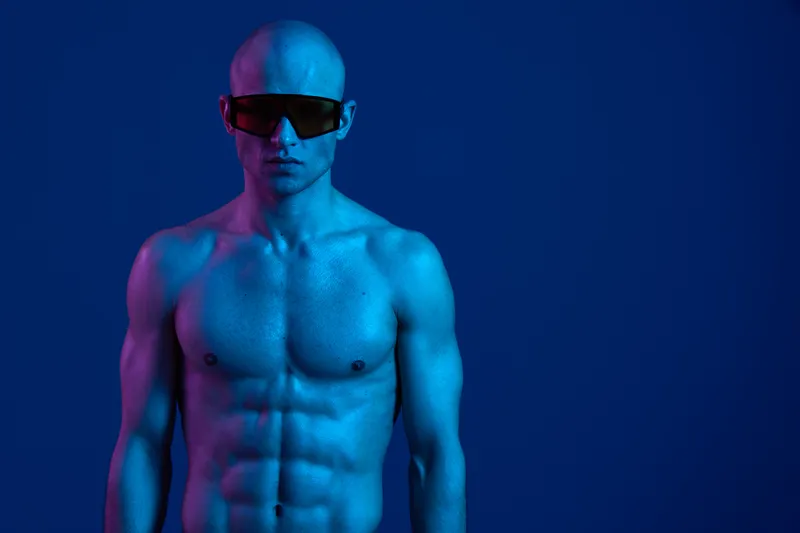 A muscular man with a blue body paint and sunglasses, exuding confidence against a vibrant backdrop. The image is striking and eye-catching, perfect for conveying boldness.