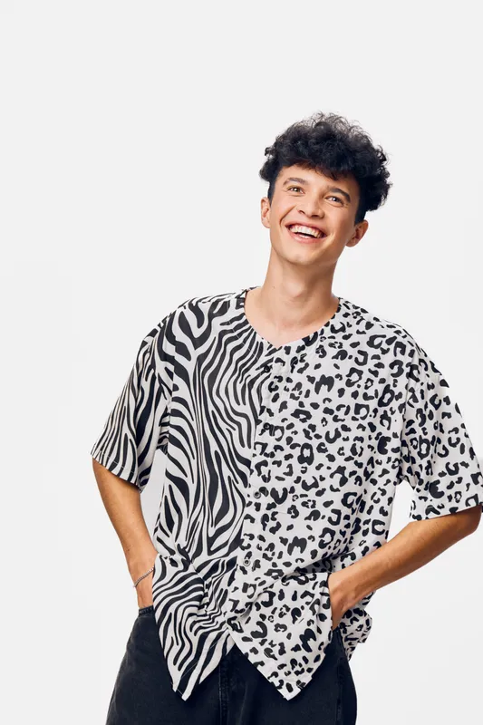 Smiling man in animal print t-shirt enjoying a carefree moment, casual style, youthful energy, fashion trend, isolated on white background, positive mood.