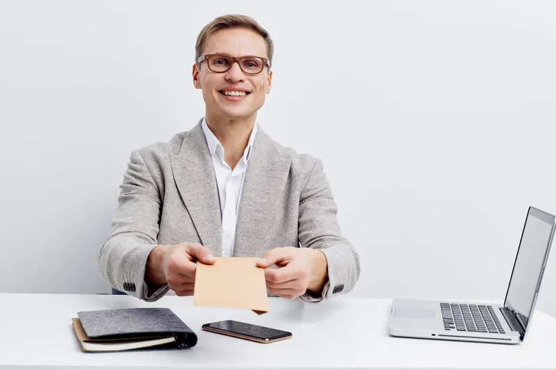 smiling man sending envelope working with laptop smartphone glasses gray jacket white background digital communication concept