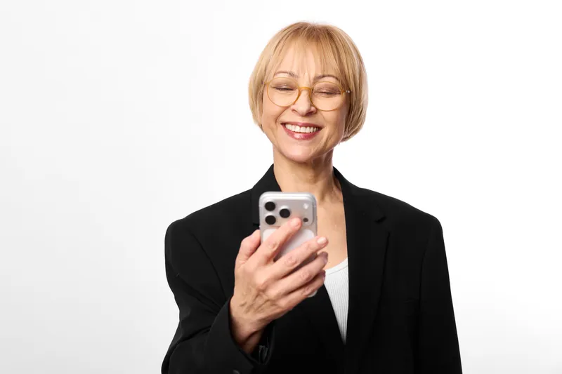 Woman holding smartphone with smile, wearing black blazer, clean business portrait on white background, showing communication and technology, digital connection, mobile messaging, professional fashion