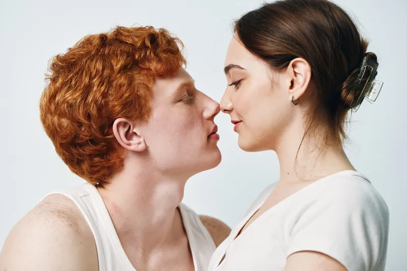 Couple, young man and woman, close together with eyes closed, intimate moment of affection and love, side view in bright studio. Relationship, connection and tenderness between partners.