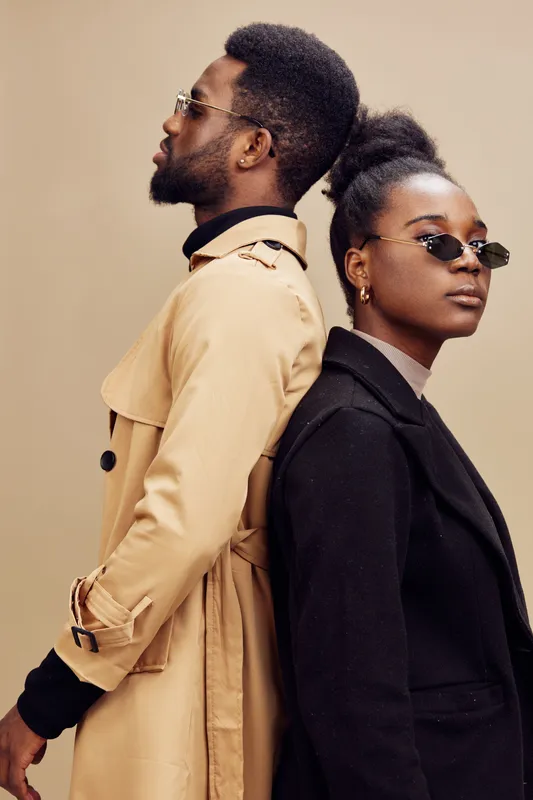 Stylish couple in contemporary fashion posing against a neutral background, showcasing elegance and sophistication with sunglasses and trendy outfits