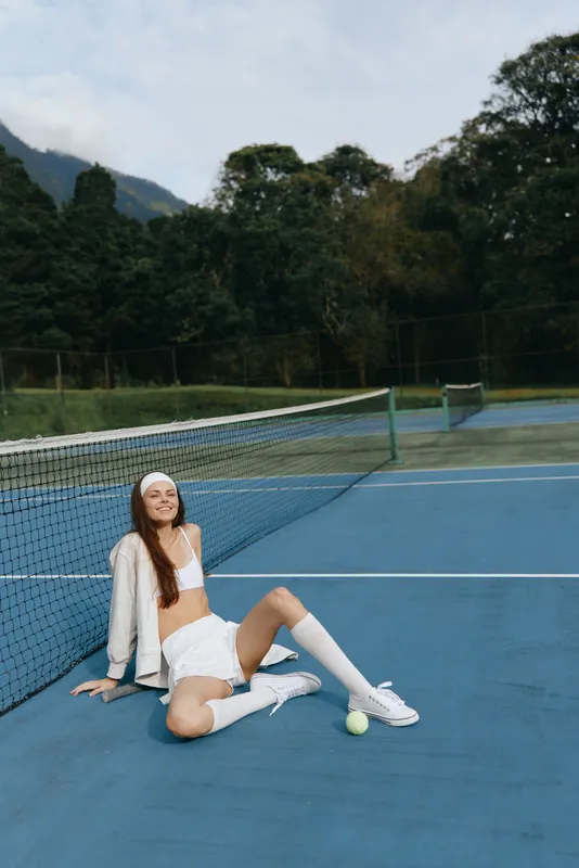 Young female tennis player wearing stylish sportswear, showcasing confidence in a serene outdoor setting, emphasizing a vibrant and energetic concept of sports