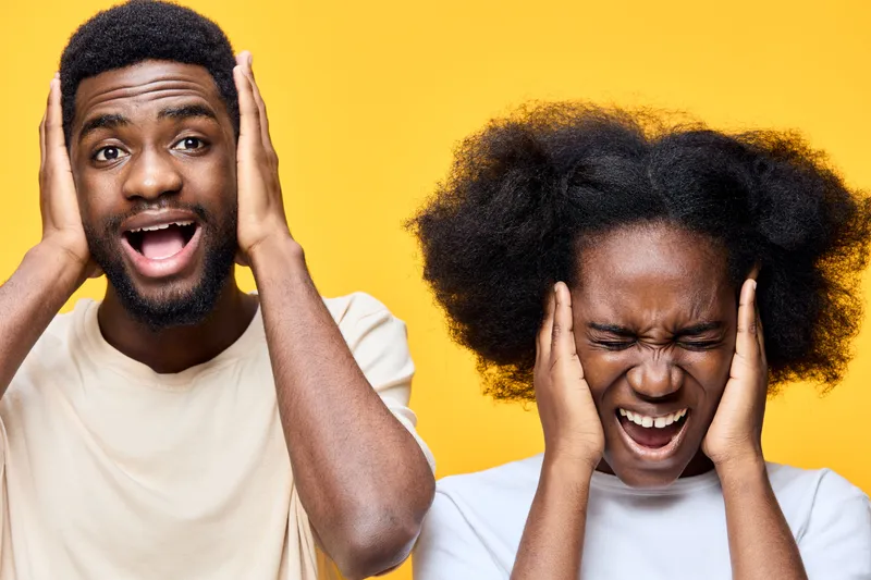 Two young adults expressing frustration and discomfort, with one covering ears and the other grimacing, against a vibrant yellow background
