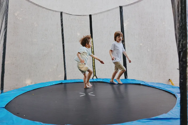 Happy children bouncing on a trampoline, enjoying a sunny day outdoors with vibrant energy and joyful laughter, embracing the spirit of playtime and fun.