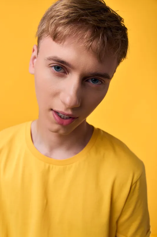 Young man, yellow background, yellow shirt, studio lighting, fashion photography, close up shot, male, casual clothing, vibrant color, cheerful expression on a bright studio set.