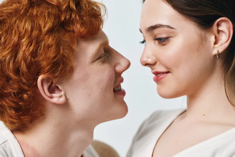 Couple, love, young man and woman looking at each other with smile for relationship, intimacy and happiness in studio. Togetherness, romance and affection with closeup face and emotions.