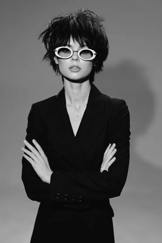 stylish woman with short hair wearing sunglasses and black blazer in black and white portrait