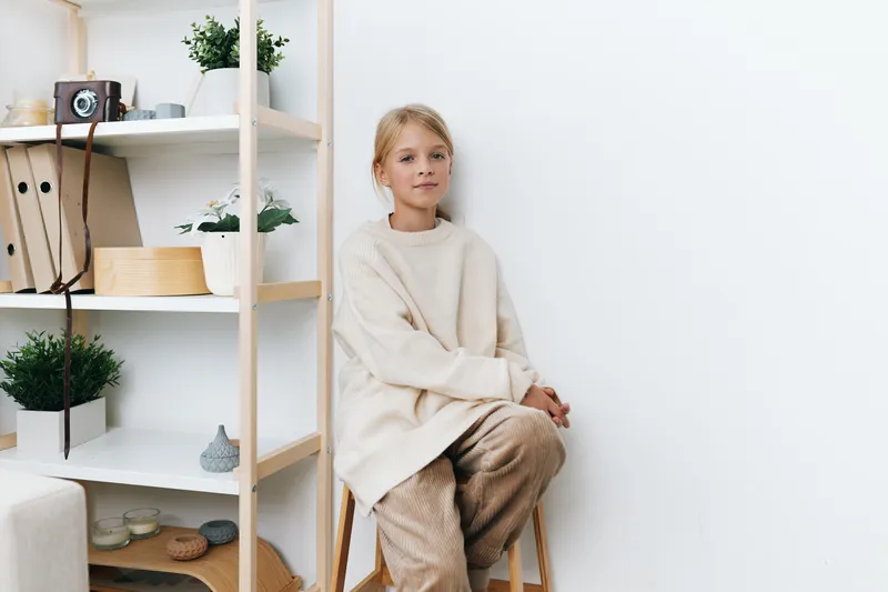 Authentic scene of a girl in a cozy sweater at home, capturing a playful school lifestyle and simple moments that feel genuine, calm, and spontaneous.