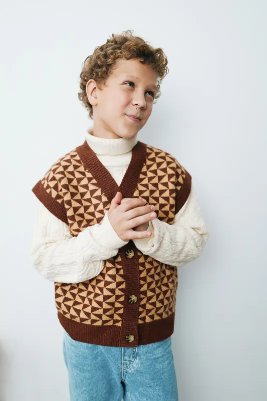 Authentic youth lifestyle scene featuring a child in a cozy knit vest, ready for play and learning, capturing genuine expression and everyday school life charm.