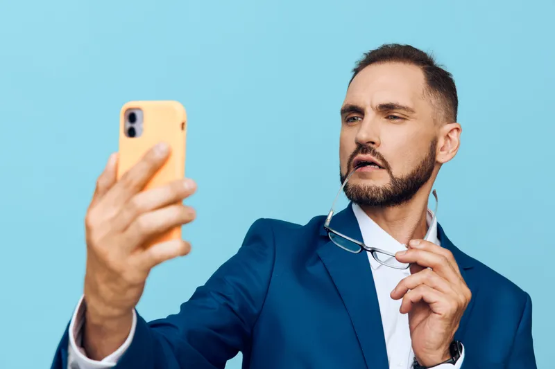 A professional businessman portrait with a vivid isolated colored background. The subject looks at a phone with focus and confidence, projecting leadership and readiness to share ideas in a dynamic