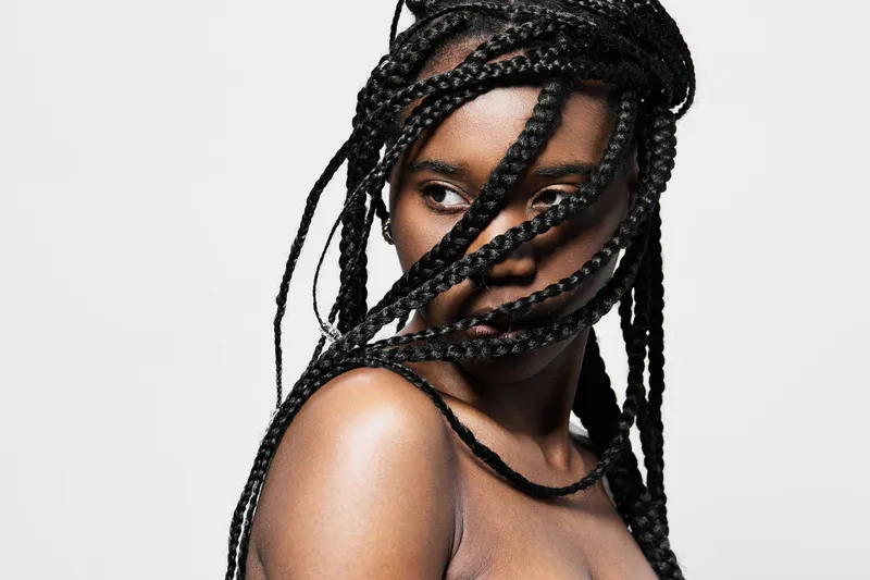 Portrait of a young woman with braided hair, showcasing beauty and confidence against a minimalistic background, ideal for fashion and beauty themes