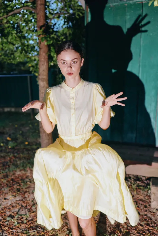 woman in vintage cream dress sitting on bench at night with dramatic shadow portrait authenticity inclusivity