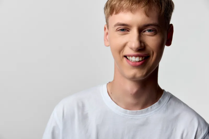 Smiling man wearing a white t shirt in a bright studio, conveying friendly confidence, casual style, and approachable vibes for lifestyle, wellness, or customer service visuals