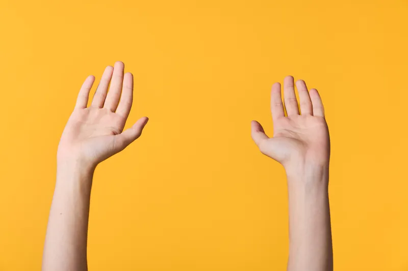 Hands raised against a bright orange background convey cheerful reception, participation and celebration in a simple scene, suggesting collaboration, energy and inclusive communication for modern