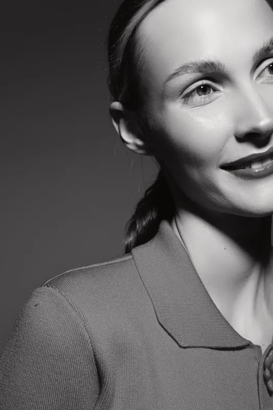 Smiling caucasian woman with pale skin and braided hair wears collared top. Close-up portrait in black and white. Concept of happiness, confidence, and natural beauty.