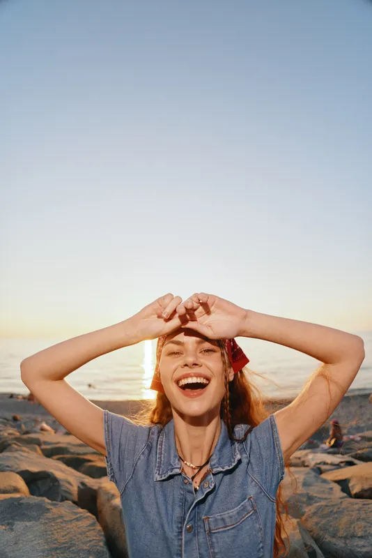 lifestyle woman in modern boho-western denim street style smiling joyfully outdoors at sunset with warm film color tones