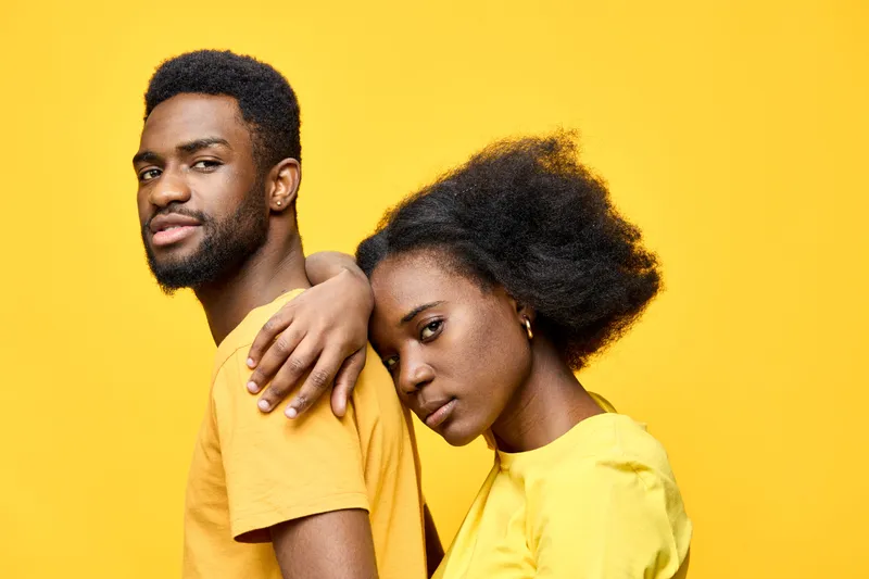 Close up portrait of a young Black couple wearing matching yellow clothing, showcasing love and connection against a vibrant yellow background