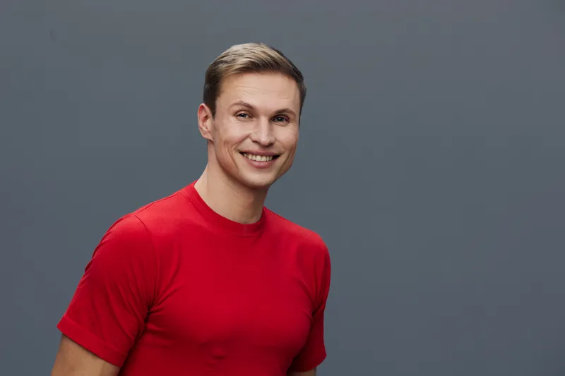 Smiling young caucasian man wear red t-shirt looking at camera studio portrait virtual communication concept
