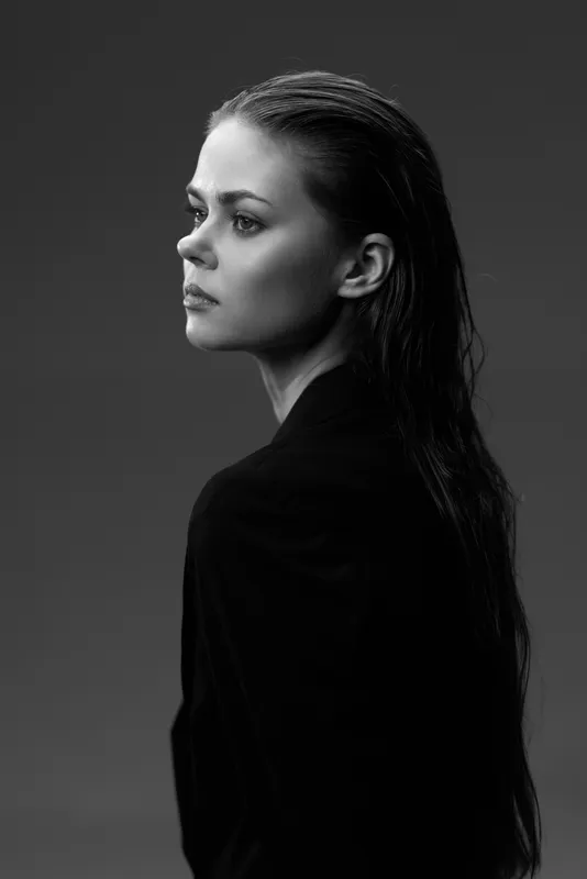 Profile of a thoughtful woman with wet hair in black and white portrait, showing emotion and calm.