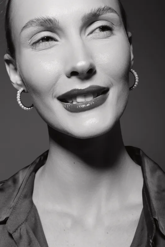 Close-up portrait of a young Caucasian woman with fair skin smiling confidently in black and white. Concept of beauty, elegance, and natural expression.