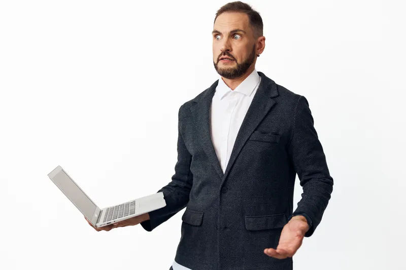 A professional man in a patterned blazer holds a laptop, displaying confidence and curiosity against an isolated colored background, portraying business expertise and forward thinking in a corporate