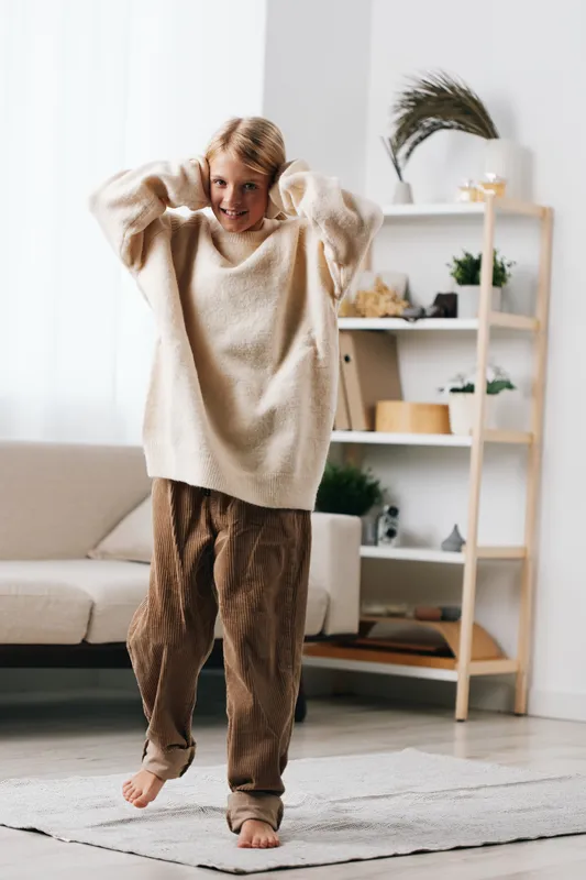 Authentic lifestyle scene featuring a child at home, playful mood, comfortable wardrobe, and everyday routine that hints at school prep and imaginative play.