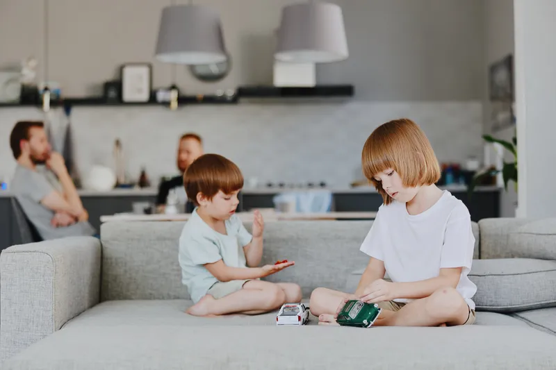 Two children playing together on a sofa, showcasing creativity and joy in a modern living room filled with natural light and warm tones.