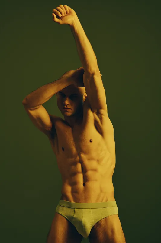 Athletic man posing confidently with strong muscles, showcasing his physique in a dramatic lighting. The image captures the essence of strength and vitality.