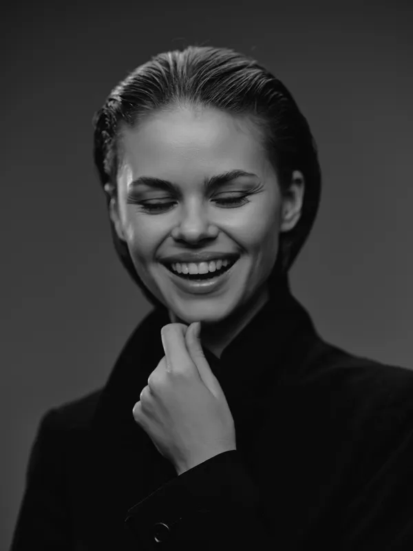 smiling woman in black and white portrait wearing dark coat showing joyful emotion