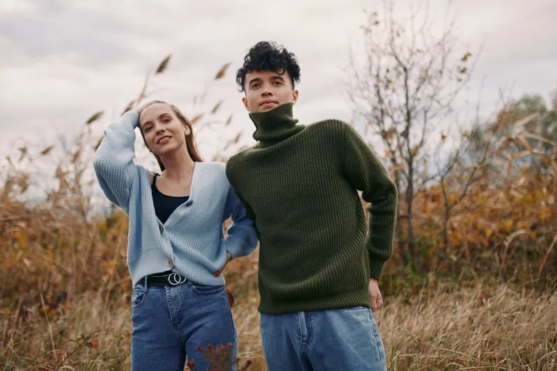 A candid outdoor moment with two friends in autumn light, showing authenticity through relaxed posture, natural textures, and a believable, warm connection.
