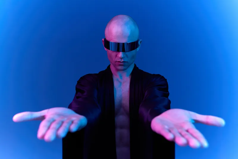 Futuristic man in black robe with hands outstretched, showcasing a vibrant light contrast between blue and purple. A striking representation of modern fashion and expression.