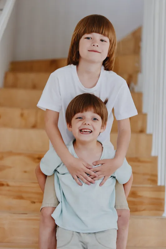 Happy boys playing on stairs, showcasing sibling bond, joy, and youthful energy in a bright home setting.