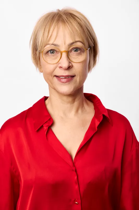 Woman portrait with glasses, smiling blonde senior in a red blouse against white studio background, closeup face and hair, calm confidence, wellness mood.