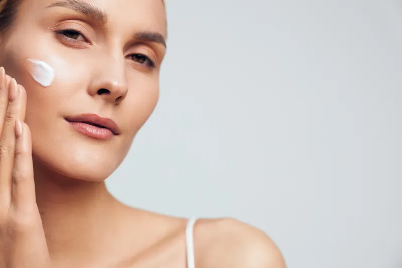 Woman, skincare, face, cream, beauty, spa, lotion, treatment, close up portrait of young female applying moisturizer to face, smooth skin, relaxed expression, light background, beauty concept