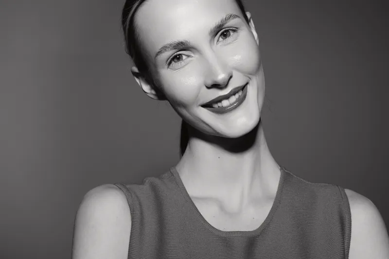 Smiling Caucasian woman with pale skin and short hair looks at camera, wearing sleeveless top. Studio portrait concept for happiness, beauty, and confidence.