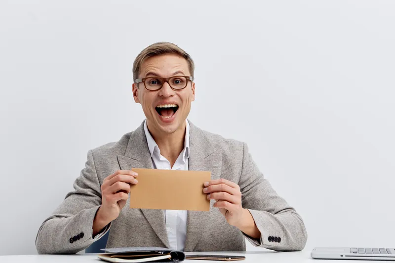 excited man holding envelope celebrate success wearing glasses checkered blazer white shirt sitting at table digital detox happy emotion clean background