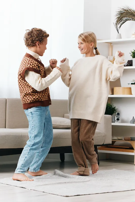 Authentic scene of children at home engaged in playful movement, showcasing joy, friendship, and everyday activity during a candid lifestyle moment, involving gentle exercise and shared discovery.