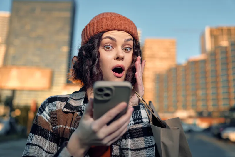 Woman phone surprise urban shopping portrait candid emotional reaction captured with authenticity and candid lifestyle vibe, golden hour glow and mindful living mood for emotional storytelling.
